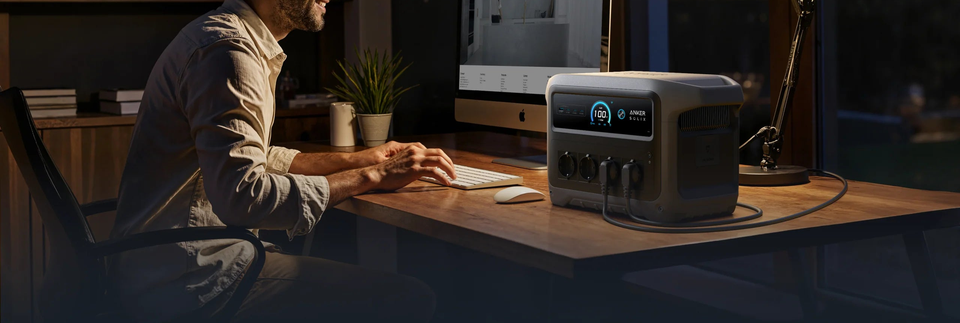 Arbeitsplatz mit einer Person am Computer und Anker SOLIX Powerstation.