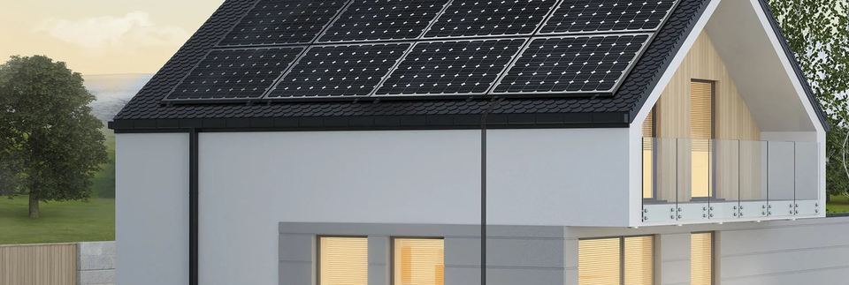 Wohnhaus mit Photovoltaikmodulen und beleuchteten Fenstern.
