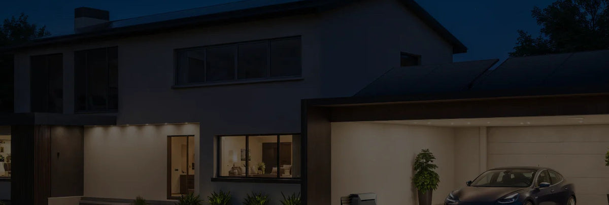 Wohnhaus mit Solaranlage und beleuchteter Garage am Abend.