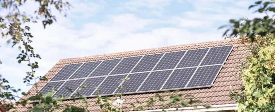 Photovoltaikanlage auf einem Hausdach zwischen Bäumen.