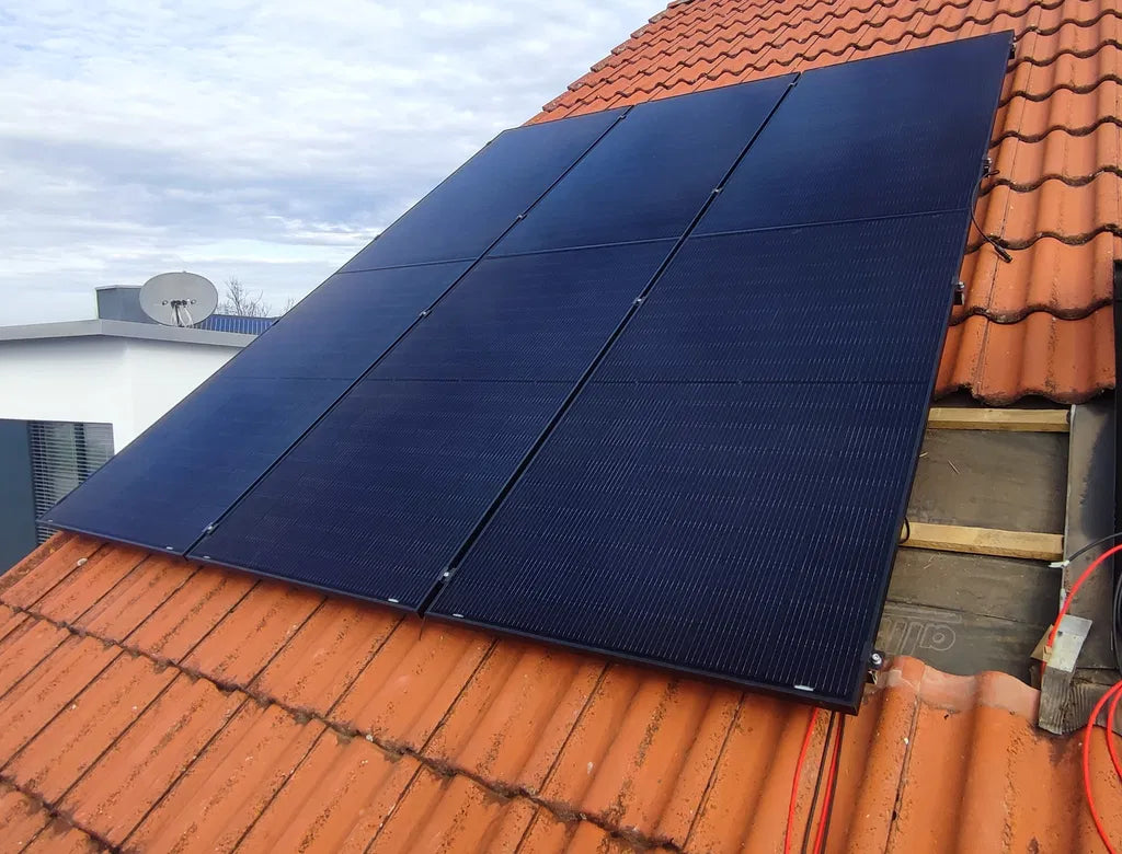 Vier Solarmodule auf einem roten Ziegeldach
