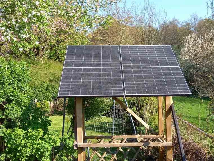 Zwei Solarmodule auf einer Holzhalterung im Garten