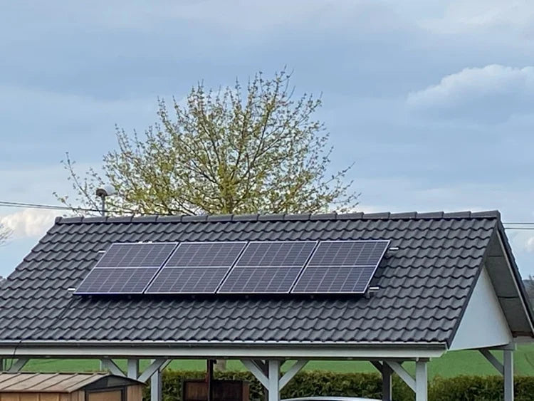 Vier Solarmodule auf einem dunklen Ziegeldach