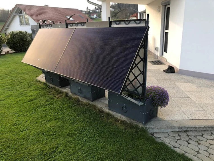 Vier Solarmodule auf einer freistehenden Halterung neben einer Terrasse
